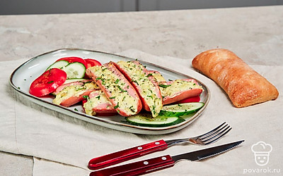 Две сосиски (1 порцию) выложите на небольшую доску для подачи, вокруг разложите дольки помидора и огурца.