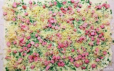 Раскатайте тесто, выложите получившуюся массу, колбасу, и сыр. Сверните все в рулет, разрежьте, смажьте желтком, и отправьте запекаться на 20 минут при температуре 180 градусов.