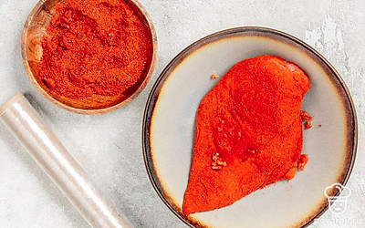 Замаринуйте курицу. В широкую и глубокую емкость положите подготовленное куриное филе. Сначала всыпьте соль, затем перец, паприку и чеснок. Тщательно вотрите маринад в курицу со всех сторон. Плотно оберните миску пищевой пленкой и держите в холодильнике 24 часа. За это время мясо должно стать более твердым.