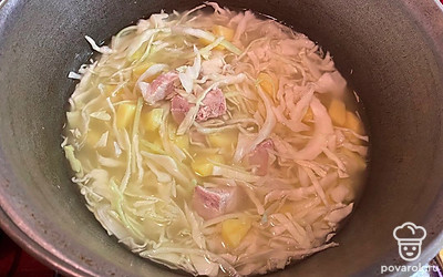 Мелко нашинковать капусту, добавить ее в кастрюлю и варить ещё 10 минут. 