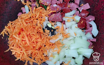 Нарезать лук и зелень и колбасу, и отправить на сковороду, предварительно разогрев ее. Натереть морковь на тёрке и тоже отправить туда же.