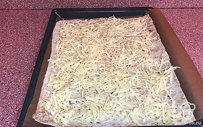 Противень застелите пергаментом. Кусок лаваша положите на противень, посыпьте тертым сыром.