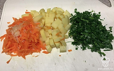 Далее нарезаем картошку кубиками, морковь натираем на крупной тёрке, а чеснок на мелкой. Зелень мелко рубим.