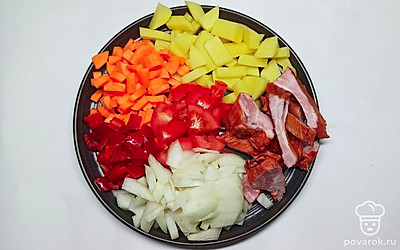 Говядину залейте водой, проварите в течение часа, добавьте промытый горох, проварите еще минут 40. Овощи очистите от кожуры, нарежьте кубиками, копченые ребрышки нарежьте брусочками.