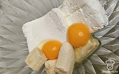 В глубокой миске смешайте творог с яйцами и бананом. 