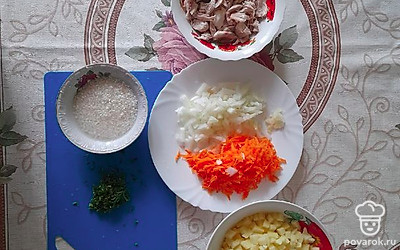 Отварите куриное мясо и разберите на кусочки. Промойте рис, овощи очистите от кожуры и вымойте в проточной воде. Натрите морковь, картофель и лук нарежьте кубиком. Покрошите зелень и пропустите чеснок через пресс.