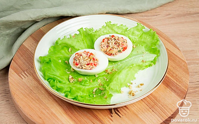 Положите яйца на лист салата, сверху присыпьте орехами. Блюдо готово украсить ваш праздничный стол!