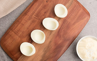 Вареные куриные яйца разрежьте вдоль на две части. Аккуратно выньте желток из каждой половинки. Белки пока отложите в сторону, а желтки разомните вилкой.