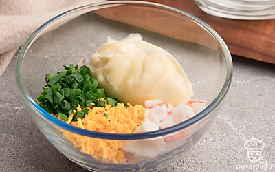 Выложите в миску измельченные крабовые палочки, плавленый сыр, зеленый лук и желтки. Добавьте майонез и все перемешайте. Посолите начинку по вкусу.