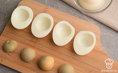 Отварные куриные яйца разрежьте вдоль пополам на две части. Аккуратно отделите желтки от белков. Половинки белков отложите пока в сторону, а вареные яичные желтки разомните вилкой.