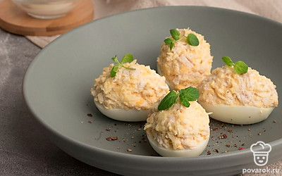 Наполните получившейся начинкой половинки яичных белков. Выложите фаршированные яйца на тарелку и украсьте свежей зеленью. Посыпьте закуску свежемолотым черным перцем. Готово. Приятного аппетита!