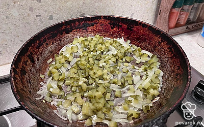 Соленые огурцы нарежьте мелким кубиком, отправьте к луку и жарьте 2 минуты.