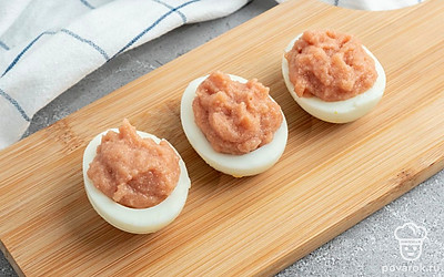 Очистите куриное яйцо и разрежьте пополам. Отделите белок от желтка, вынув последний чайной ложкой. Мелко нашинкуйте яичный белок. Смешайте в отдельной миске майонез, яичный желток мясо минтая для начинки, добавьте соль и перец по вкусу. Выложите начинку в яичный белок, равномерно распределите ее внутри.