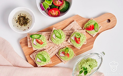 Подавайте закуску из авокадо на хлебцах, украсив их листиками микрозелени.