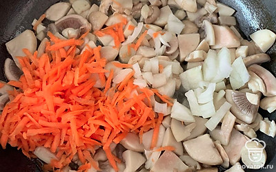 К грибам добавляем лук и тертую морковь.