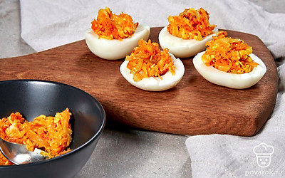 Приготовьте закуску. Разрежьте яйца на половинки и удалите из них желтки. Разомните желтки вилкой. Добавьте к остывшим луку и морковке размятые желтки, заправьте майонезом и смешайте. Получившейся начинкой нафаршируйте яйца.