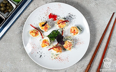 Блюдо оформите листьями салата. Готовые фаршированные половинки перепелиных яиц с помощью шпажек соедините в целое вместе с одним кружочком маслины и помидора черри. Затем разложите на блюде.