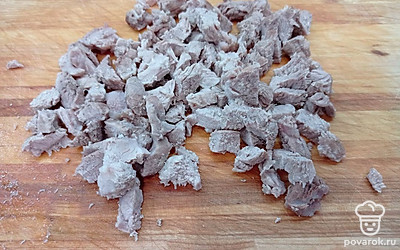 Свинину достать из бульона и нарезать кубиками.