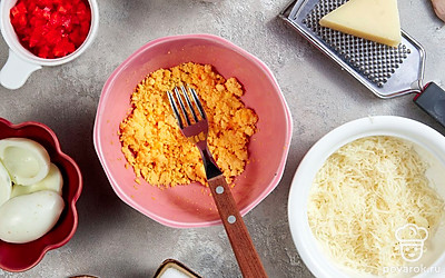 Подготовьте ингредиенты. Раздавите чеснок. Мелко натрите сыр. Болгарский перец нарежьте маленькими кубиками. Разрежьте яйца на половинки и выньте желтки. Разомните желтки вилкой.