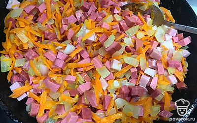 Обжарьте лук с морковкой до золотистого цвета. Затем добавьте к ним кубики мясных деликатесов, перемешайте и обжарьте 7 минут.
