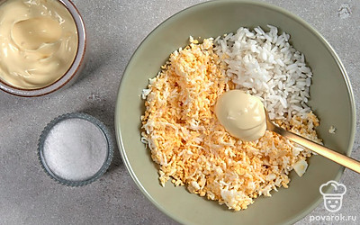 Займитесь начинкой. Куриные яйца пропустите через терку с мелкими зубцами. Соедините их с рисом, сдобрите майонезом, перемешайте.