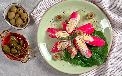 Сервировочную тарелку застелите салатными листьями, на зеленую подложку выложите крабовые палочки, фаршированные рисом и яйцом.