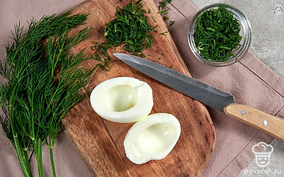 Подготовьте ингредиенты. Разрежьте яйца на половинки и удалите из них желтки, которые нужно размять вилкой. Нашинкуйте укроп.