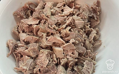 Достать из кастрюли мясо, порезать небольшими кусочками и вернуть его обратно в кастрюлю.