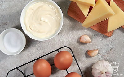 В небольшую кастрюлю налейте воду, опустите в нее яйца и поставьте на огонь. Доведите до кипения, после чего варите яйца еще 10 минут на медленном огне до готовности. Кипяток слейте и залейте содержимое кастрюли холодной водой, чтобы яйца лучше очистились. Почистите чеснок. Помойте петрушку и огурец для подачи, порежьте огурец тонкими ломтиками.