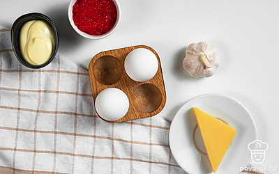 Яйца куриные промойте и сварите вкрутую, затем охладите и очистите от скорлупы. Чеснок очистите от шелухи и пропустите через пресс. Икру разделите на 4 равные части. Базилик помойте и просушите. Маслины разрежьте пополам.