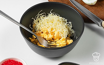 Подготовьте яйца и компоненты начинки. Яйца разделите на половинки и достаньте из них желтки. Измельчите их вилкой в отдельной миске. Затем натрите сыр на терке и добавьте его к желткам.