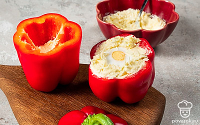 Начините перцы. Выложите в каждый перец часть сырной массы и утрамбуйте, оставляя выемку. Поместите в нее целое вареное яйцо. Доложите оставшийся сыр в соусе. Поставьте в холодильник на 2 часа для охлаждения и пропитки.