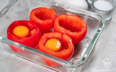 Подготовьте блюдо к запеканию. Из каждого помидора аккуратно выньте мякоть. Перья лука нарежьте тонкими кольцами. Растительным маслом смажьте форму для запекания, поставьте в нее помидоры отверстием вверх. После этого разбейте по одному яйцу в каждый помидор.