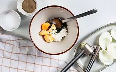 Начните приготовление закуски. Очищенные яйца разрежьте вдоль, желтки извлеките и переложите в отдельную миску. Туда же добавьте мягкий сливочный сыр, измельченный укроп, чеснок, пропущенный через пресс, соль и перец по вкусу. Все ингредиенты тщательно перемешайте.