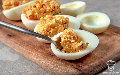 Приготовьте блюдо. Яйца разрежьте пополам, желтки отделите от белков и переложите их в отдельную емкость. К желткам добавьте обжаренные овощи. Заправьте ингредиенты майонезом, солью и перцем по вкусу, тщательно перемешайте. Готовой начинкой наполните яичные белки.