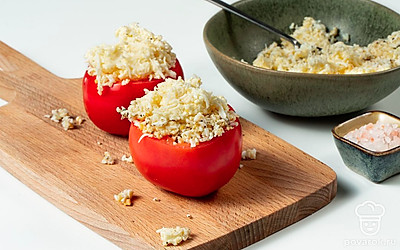 Приготовьте блюдо. У помидоров удалите плодоножки, после чего разрежьте овощ пополам. Используя нож, извлеките из плодов мякоть, оставляя только стенки. Заполните помидоры яично-сырной начинкой, после чего уберите их в холодильник на 10 минут.