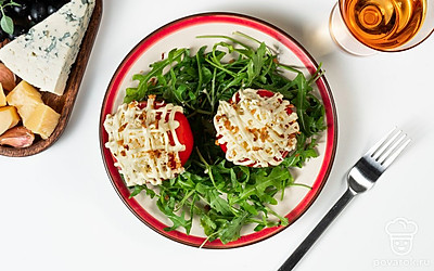 Готовые фаршированные помидоры выложите вдоль на прямоугольную тарелку. Украсьте закуску листьями кинзы, после чего подайте ее к столу.