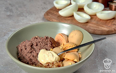 Подготовьте начинку. Яйца сварите вкрутую, аккуратно снимите шелуху. Разрежьте вдоль пополам, выньте желток. Измельчите его. Отварите куриную печень в подсоленной воде до готовности 15-20 минут. Прокрутите через мясорубку. Лук обжарьте до золотистого цвета. Смешайте с желтком и куриной печенью. Посолите, поперчите. Заправьте майонезом.