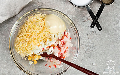 Подготовьте начинку. Смешайте в миске измельченные яйца, крабовые палочки, тертый сыр. Посолите, поперчите и добавьте майонез. Тщательно перемешайте.