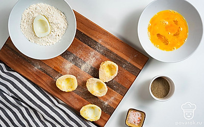 Запанируйте яйца. Возьмите три глубокие миски. В первую всыпьте муку и чесночный порошок, во вторую разбейте два сырых яйца и добавьте 1 ч. л. воды, в третью выложите панировочные сухари. После этого возьмите половинки белков вареных яиц и обваляйте их во всех мисках: сначала в муке, затем в яйцах и в конце в сухарях. Подготовленные половинки выложите на тарелку.