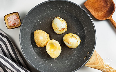 Приготовьте закуску. В сковороду влейте растительное масло и разогрейте. Когда масло раскалится, выложите в него подготовленные яичные белки и обжарьте их в течение 2-3 минут до золотистой корочки. Готовые половинки выложите на тарелку и посыпьте солью. В конце нафаршируйте готовые яйца начинкой.