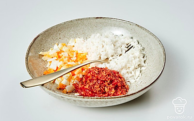 Подготовьте начинку. Яйца и петрушку измельчите. Репчатый лук мелко нарежьте и слегка обжарьте на разогретой, смазанной маслом сковороде. Спустя 5 минут жарки добавьте к луку томатную пасту и пассеруйте еще 2 минуты. Все готовые ингредиенты, включая рис, смешайте в одной миске.