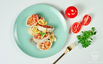 Готовых кальмаров с рисом и яйцом выложите на блюдо и украсьте ароматной свежей зеленью.