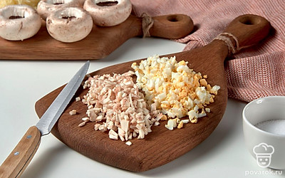 Подготовьте шампиньоны. У грибов аккуратно вырежьте ножки, стараясь не поломать шляпки. Ножки шампиньонов и вареное яйцо очень мелко порежьте. Сыр измельчите на терке. Смешайте грибы, яйца, сыр, соль и майонез.