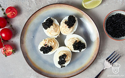 Подавайте фаршированные яйца на праздничный стол, украсив их четвертинками помидоров черри.