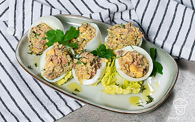 На прямоугольную тарелку выложите листья салата и на них разложите фаршированные яйца.