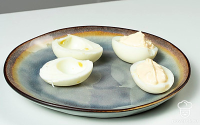 Нафаршируйте яйца. Желтки натрите на мелкой терке или просто разомните вилкой. Соедините с чесноком и майонезом. Добавьте соль. Перемешайте. Выложите начинку в половинки яиц.