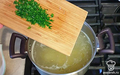 Петрушку мелко нарежьте и отправьте в бульон вместе с нарезанным куриным филе. Дайте прокипеть около двух минут.
