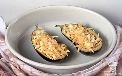 Нафаршируйте и запеките баклажаны. Форму для запекания смажьте растительным маслом. Баклажаны наполните начинкой и выложите в подготовленную форму. Поставьте в разогретую до 180 градусов духовку на 25 минут.