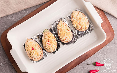 Баклажаны разрежьте пополам, выньте столовой ложкой середину и нафаршируйте полученной начинкой. Застелите форму для запекания фольгой. Выложите в нее баклажаны и запекайте их в разогретой до 180 градусов духовке в течение 15-20 минут.